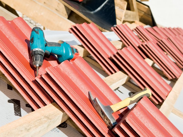 Dachdecker Blaue Bohrmaschine und Hammer auf roten Dachziegeln beim Dachbau
