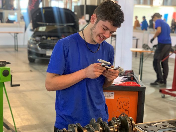 WorldSkills Italy: Lyon als Ziel Junger Mann misst autoteil mit Messschieber in Werkstatt