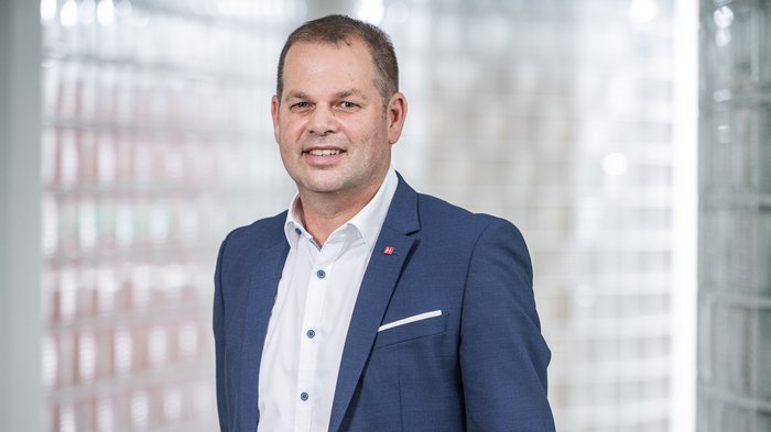 Soddisfazione di lvh.apa per il forte risultato elettorale a Bolzano Uomo in abito blu sorridente davanti a parete di vetro