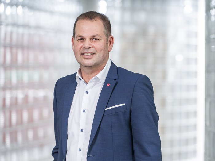 Berufsschulstart 2025: Südtirol setzt auf duale Ausbildung und frühe Praxisorientierung Mann in blauem Anzug vor Glasbausteinwand lächelnd