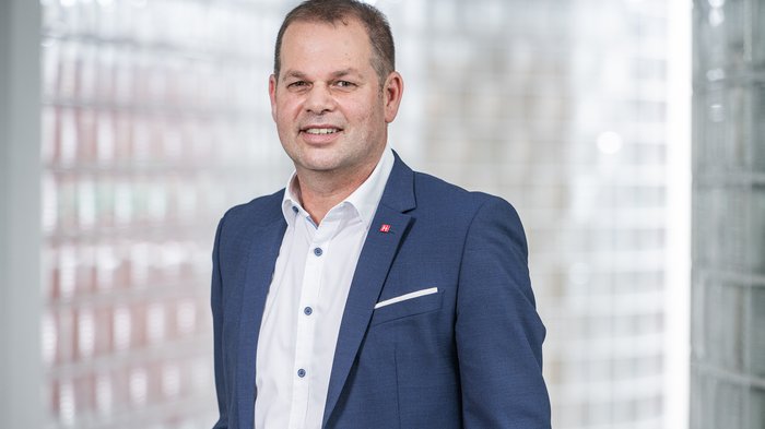 Berufsschulstart 2025: Südtirol setzt auf duale Ausbildung und frühe Praxisorientierung Mann in blauem Anzug vor Glasbausteinwand lächelnd