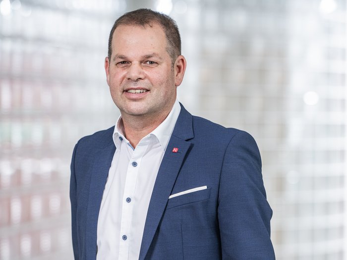 Soddisfazione di lvh.apa per il forte risultato elettorale a Bolzano Uomo in abito blu sorridente davanti a parete di vetro