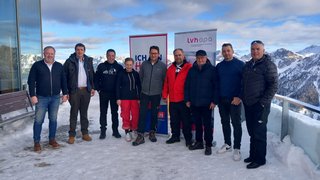 News Gruppe von zehn Personen steht auf schneebedecktem Balkon mit Bergen im Hintergrund