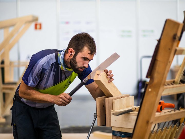 Holzbaumeister und Zimmerer Mann sägt einen Holzblock im Workshop mit einer Handsäge