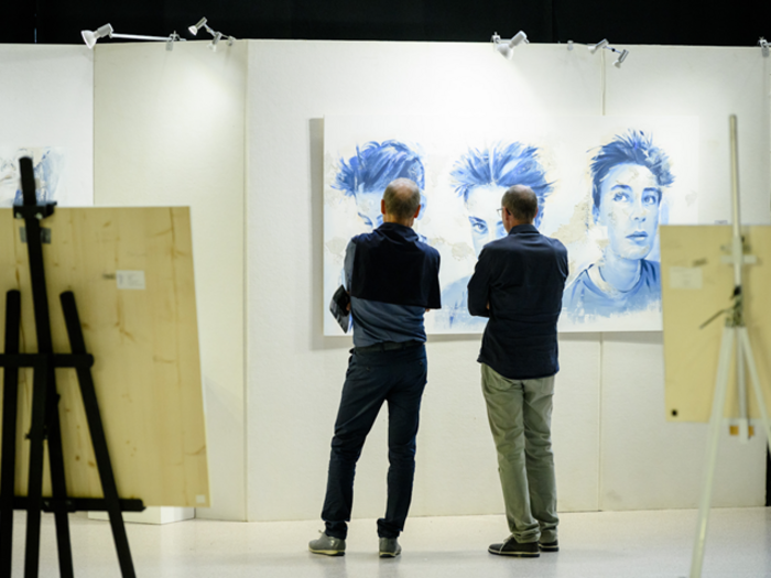UNIKA - Vernissage Due uomini osservano ritratti blu in una galleria d'arte