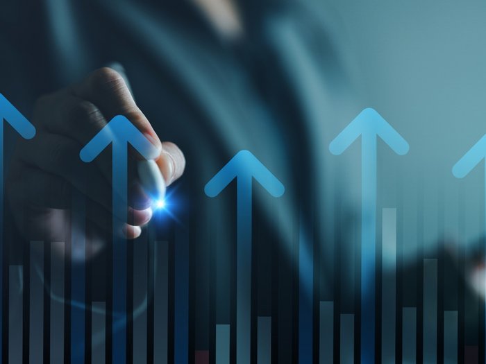 Hyperabschreibung 2026–2028: Investitionen werden zum Wettbewerbsvorteil Hand zeigt auf steigende Pfeile und Balkendiagramm im Geschäftskontext