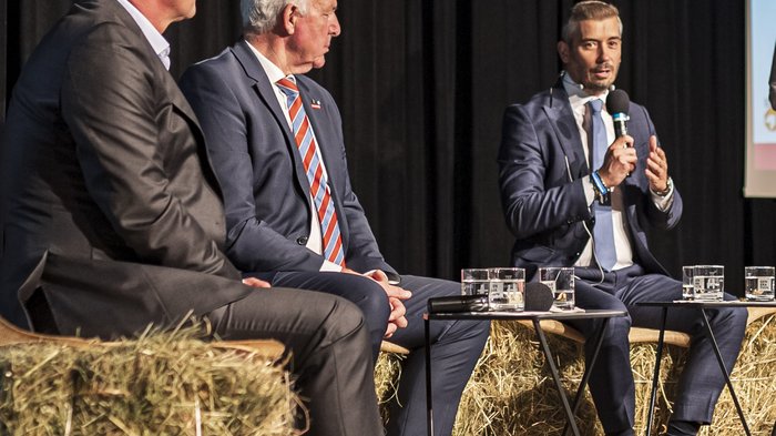 Tag des Handwerks - Jugend als Schlüssel für unsere Zukunft Diskussion mit drei Männern in Anzügen auf Strohballen sitzend bei einem Event