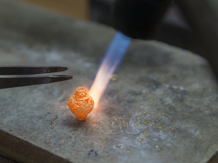 Orafi e argentieri Orafo modella un gioiello d'oro finemente lavorato con una fiamma