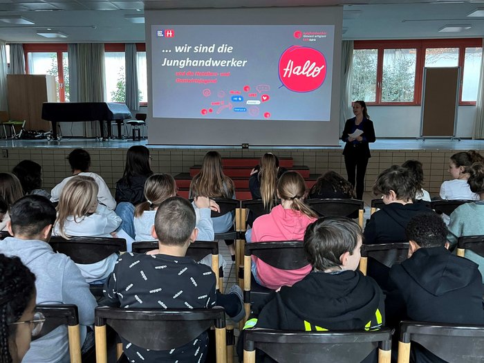 „Mit unseren Ausbildungen ist vieles möglich!“ Schüler schauen einer Präsentation der Junghandwerker in einem Klassenzimmer zu