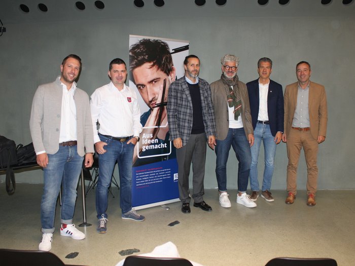 La rotta adeguata verso il futuro Sei uomini in piedi davanti a un muro grigio vicino a un banner pubblicitario