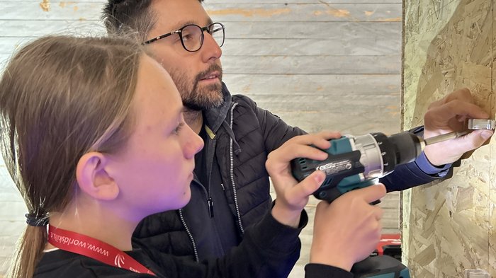 SkillsDay nella Val d'Ega: scoprire l'artigianato, scoprire talenti Donna impara da uomo a usare trapano a batteria durante formazione elettricista