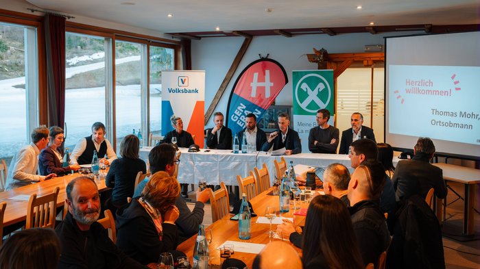 Successo della riunione comunale del gruppo lvh.apa a Dobbiaco: un anno ricco di impegno e collaborazione Persone in riunione con relatore e presentazione in una sala