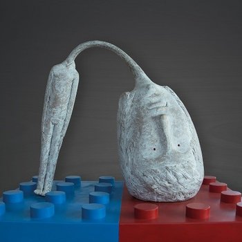 Ivan Art Abstrakte Skulptur mit gesichtsförmiger, gebogener Form auf blau-rotem Bauklotz