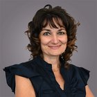 Familie und Soziales Porträt einer lächelnden Frau mit lockigem Haar vor grauem Hintergrund