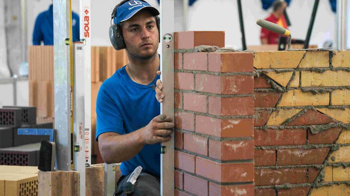 EuroSkills 2023: adesso bisogna concentrarsi! Muratore controlla con livella una parete in mattoni
