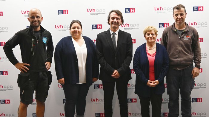 Für die Zukunft: Die Arbeitsgruppe der italienischen Mitglieder im lvh trifft italienischen Bildungsdirektor Fünf Personen posieren vor einer LVH-Generation H Werbewand