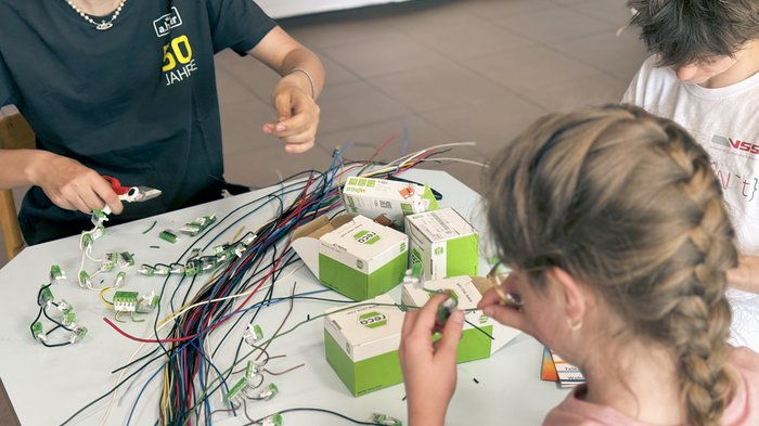 „Anpacken und Gewinnen“ – Eppans erster Handwerksparkour begeistert! Kinder arbeiten zusammen an elektrischen Kabeln und Steckverbindern auf einem Tisch