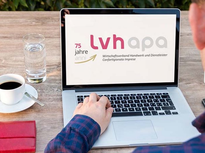 Über 400 Webinar-Anmeldungen, die Tendenz ist steigend Mann arbeitet am Laptop mit LVH APA Webseite, Kaffeetasse und Glas Wasser auf Tisch