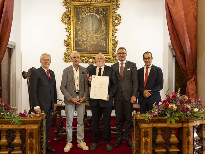 Premio Economia 2026: premiate 8 aziende associate lvh.apa Cinque uomini in abiti formali in una stanza elegante con fiori, uno tiene un certificato