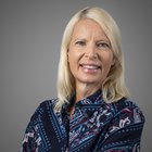 Maßschneider Porträt einer lächelnden blonden Frau vor grauem Hintergrund