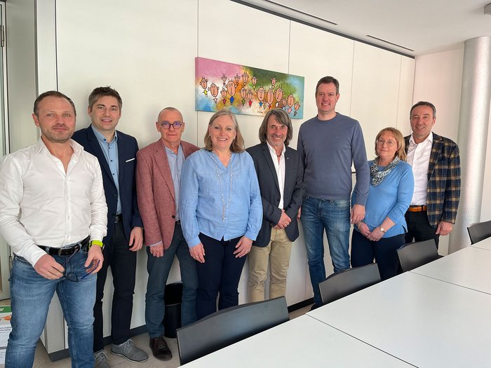 Ein Schritt zur Stärkung der territorialen Gesundheitsversorgung Acht Personen stehen nebeneinander in einem modernen Besprechungsraum