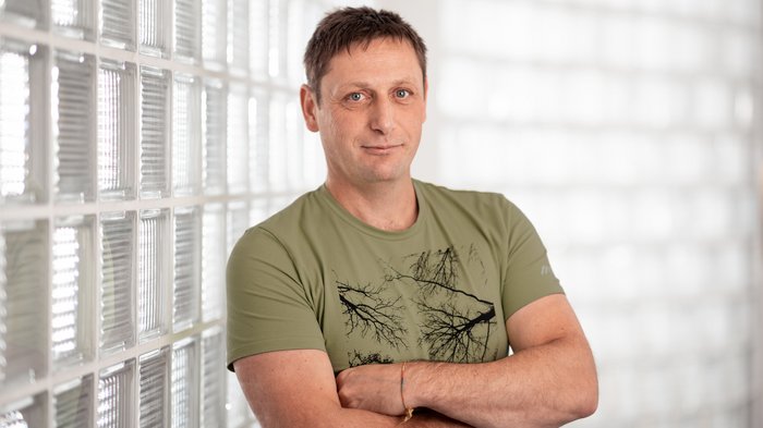 Mathias Piazzi als lvh-Bezirksobmann bestätigt Mann mit grüner T-Shirt steht vor eine Glaswand mit verschränkten Armen