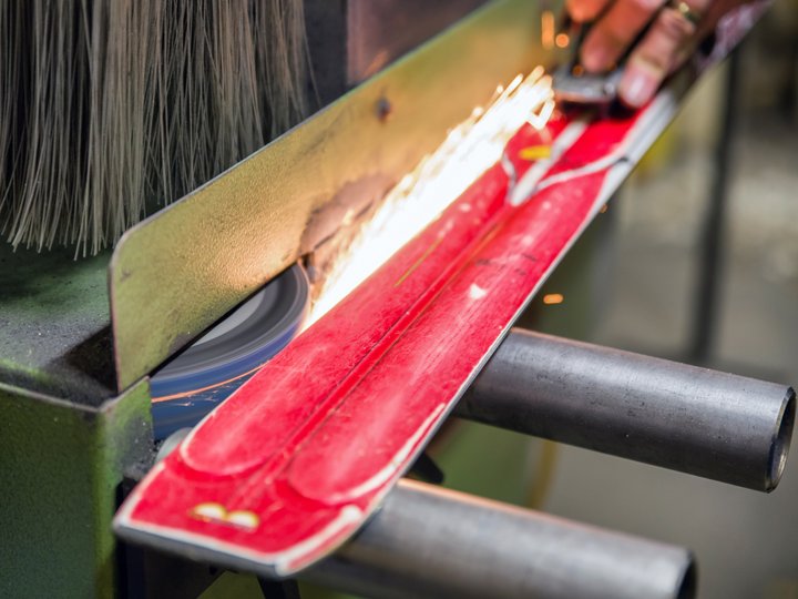 Tecnici manutenzione articoli sportivi Lucidatura del bordo di uno sci rosso con scintille