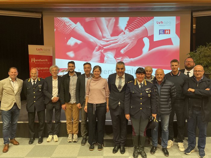 Mietwagen- und Taxiunternehmer/innen im Austausch Gruppenfoto von 13 Personen vor Präsentationsbildschirm bei einer Veranstaltung