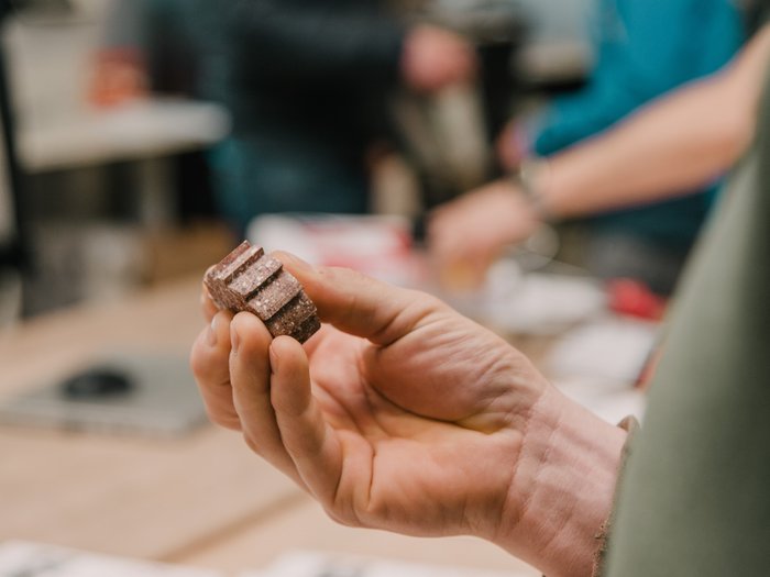© MakerSpace, lvh.apa, Fiorentino Hand hält kleine, braune geriffelte Schokolade oder Snackstückchen