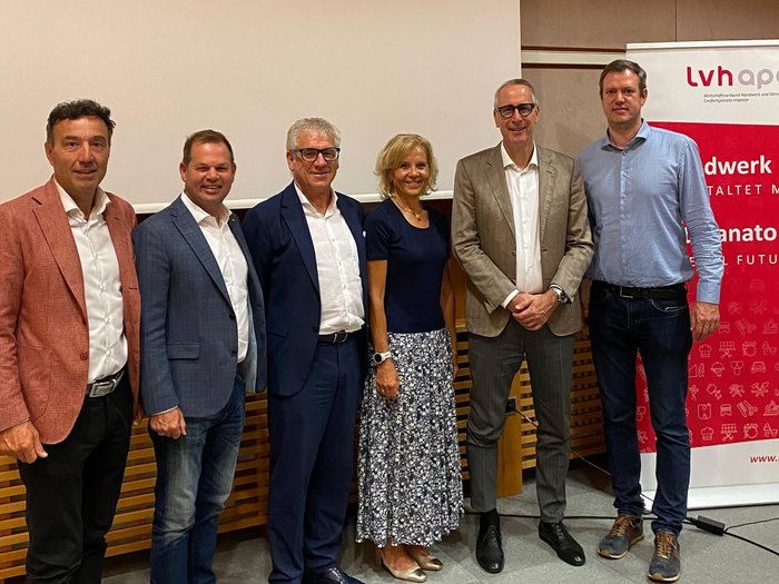 Mitreden. Mitgestalten. Mitbestimmen – lvh stärkt Austausch mit Südtirols Gemeinden Sechs Personen posieren vor einer Leinwand und einem Lvh Apa Banner