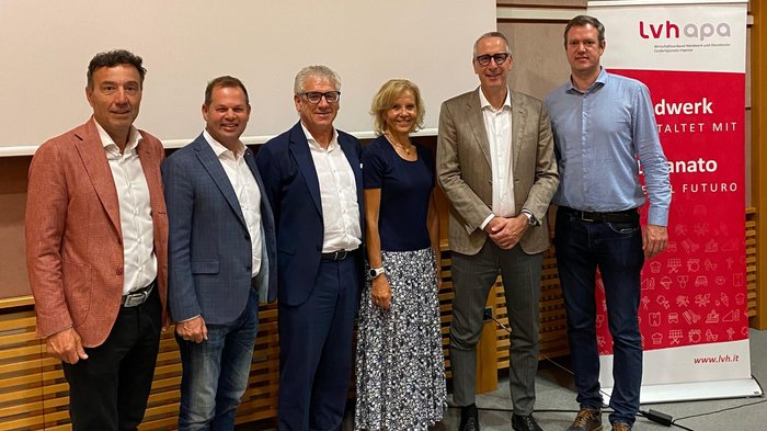 Mitreden. Mitgestalten. Mitbestimmen – lvh stärkt Austausch mit Südtirols Gemeinden Sechs Personen posieren vor einer Leinwand und einem Lvh Apa Banner