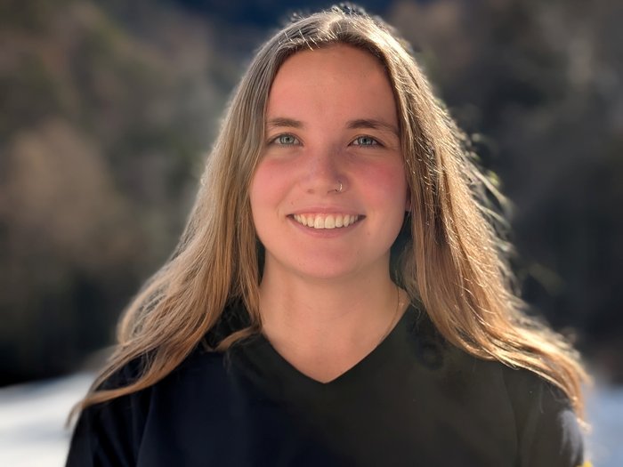 Handwerk ist weiblich – und selbstbewusst Junge Frau mit langem Haar lächelt vor unscharfem Naturhintergrund