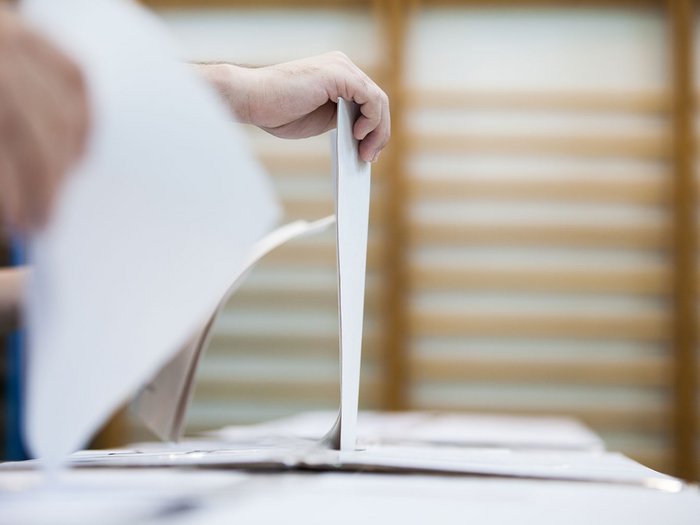 Die Justiz ist auch ein Wirtschaftsthema. Wählen gehen ist wichtig! Referendum am 22. und 23. März 2026 Eine Person wirft einen Stimmzettel in eine Wahlurne