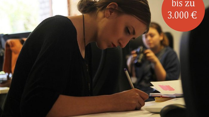 Chancengleichheit: Förderpreise für wissenschaftliche Arbeiten - bis 28.02.2025 Junge Frau schreibt konzentriert an einem Tisch im Büro