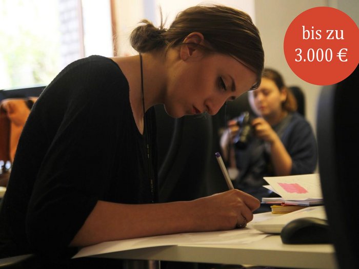 Chancengleichheit: Förderpreise für wissenschaftliche Arbeiten - bis 28.02.2025 Junge Frau schreibt konzentriert an einem Tisch im Büro