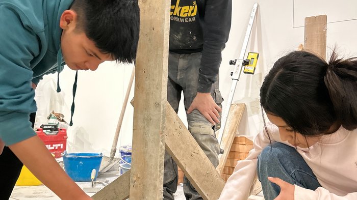 Vivere da vicino l'esperienza dell'artigianato: i mestieri pratici incontrano il futuro in Val Gardena Tre persone costruiscono con mattoni e malta in un ambiente interno