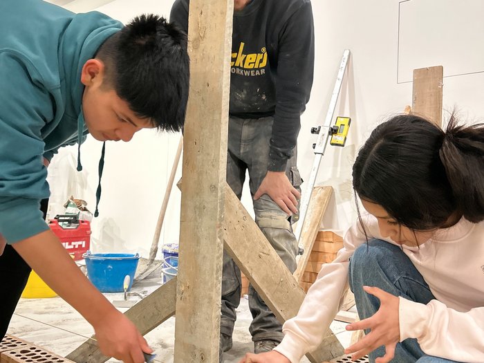 Handwerk hautnah erleben: Praxis trifft Zukunft in Gröden Drei Personen bauen mit Ziegeln und Mörtel in einem Innenraum
