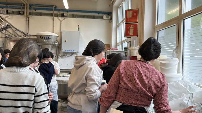 Scegliere il mestiere giusto Persone con cuffie e grembiuli in una cucina industriale o area di produzione.