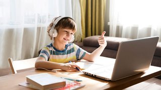 News Junge mit Kopfhörern beim Lernen am Laptop zeigt Daumen hoch