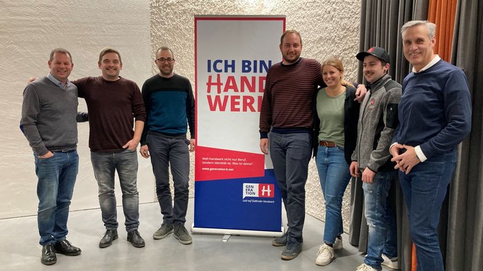 Beständigkeit in Prad Gruppe von sieben Personen steht vor Banner mit Schrift Ich bin Handwerker