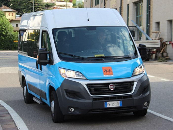 Mietwagenunternehmer: noch nie dagewesene Ausfälle Blauer und weißer Kleinbus fährt auf Straße in städtischer Umgebung