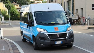 News Blauer und weißer Kleinbus fährt auf Straße in städtischer Umgebung