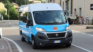 News Blauer und weißer Kleinbus fährt auf Straße in städtischer Umgebung