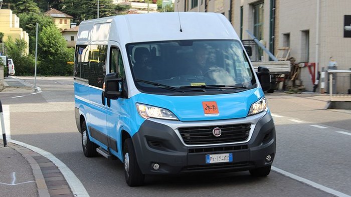 „Nur nicht auf Kosten der Kinder“ Blauer und weißer Kleinbus fährt auf Straße in städtischer Umgebung