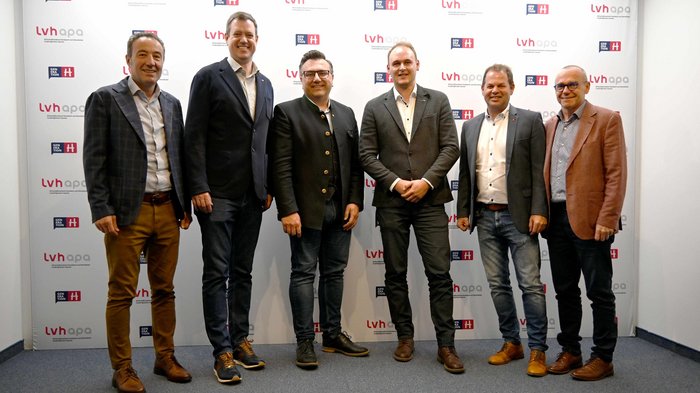 Der lvh im Dialog mit der Freien Fraktion Sechs Männer stehen vor einer Wand mit LVH-Logos für ein Gruppenfoto