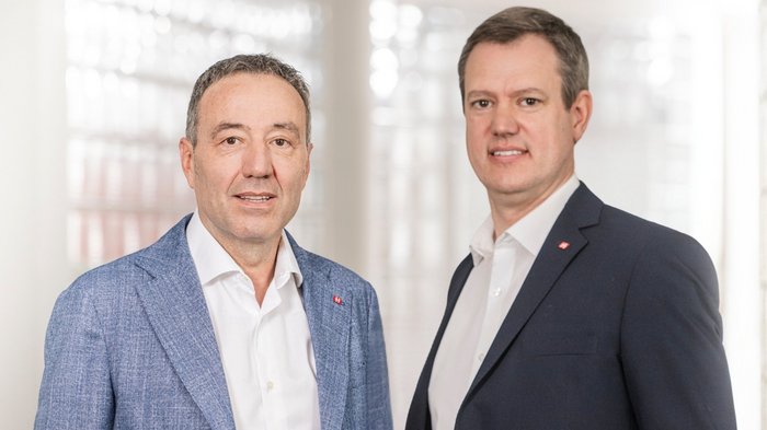 Innovationsförderung: Wichtiger Schritt zur Stärkung kleiner Unternehmen und Start-ups Zwei Männer in Anzügen vor einem hellen, modernen Hintergrund