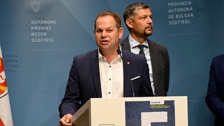 News Mann spricht an einem Rednerpult bei einer Veranstaltung in Südtirol