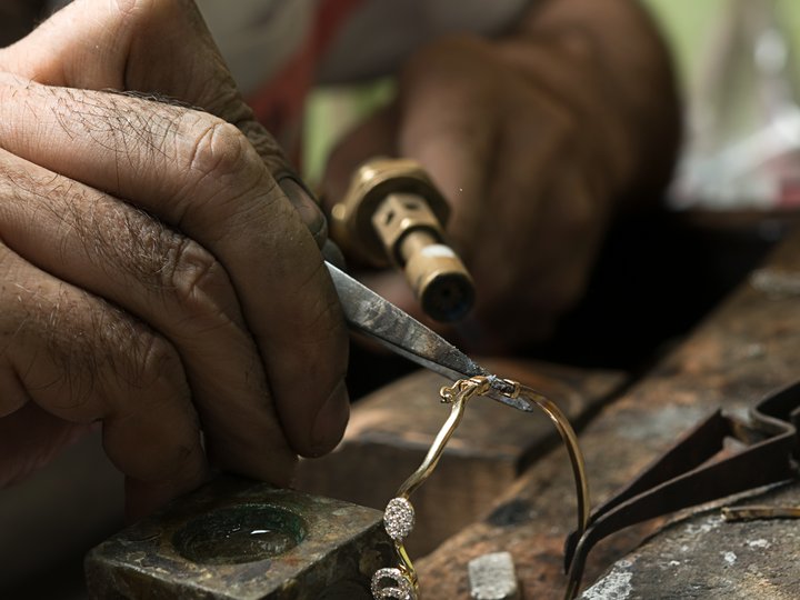 Gold- und Silberschmiede Handwerker repariert mit Werkzeug eine vergoldete Brille