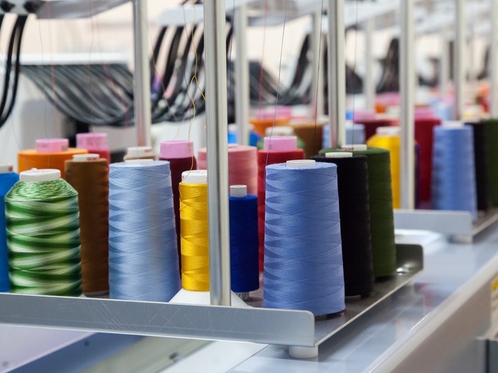 Maßschneider Bunte Garnrollen auf einem industriellen Nähmaschinenstativ