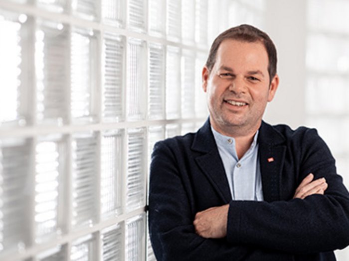 Handwerk in Bozen: Gesprächsaustausch mit Caramaschi Mann mit verschränkten Armen vor Glaswand in heller Umgebung